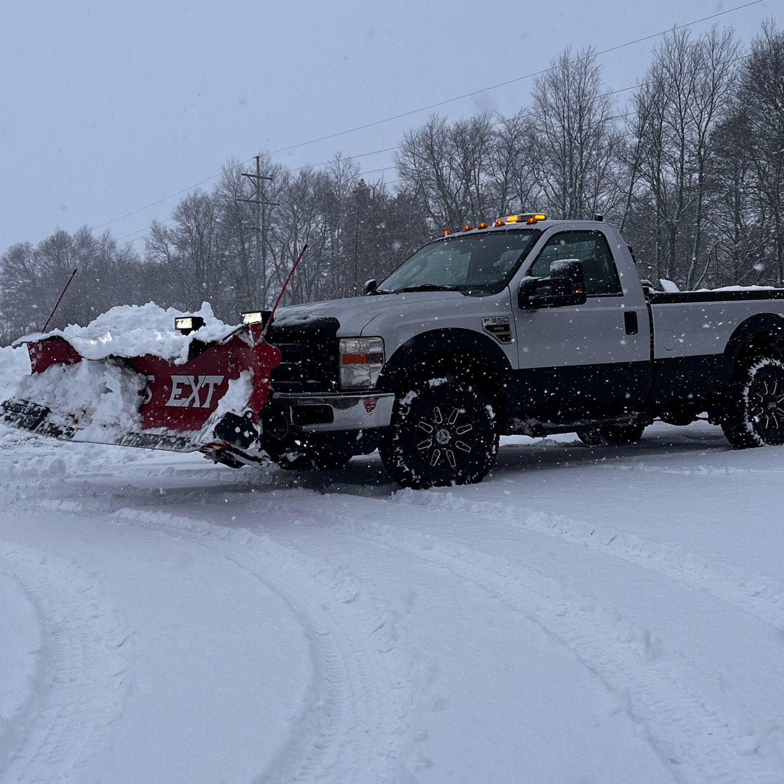 Freedom Lawn Care & Snow Removal plow truck pushing snow with a red V-plow on a snowy lot